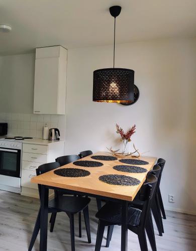 a dining room table with black chairs and aendant light at Apartment Naavis in Rovaniemi