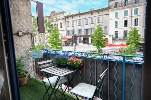 a balcony with a bench and flower pots on it at Hôtel-restaurant le Palais in Apt