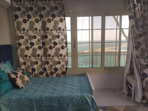 a bedroom with a bed and a window with a view at شقة فاخرة علي البحر مباشرة لوران الاسكندرية in Alexandria