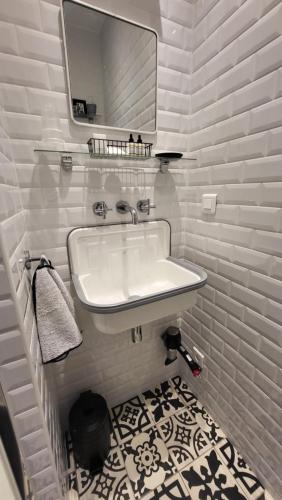 ein weißes Badezimmer mit Waschbecken und Spiegel in der Unterkunft Chez Pépé Merle - Chambres d'hôtes dans le quartier du Père Lachaise in Paris
