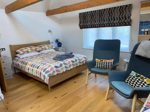 a bedroom with a bed and two chairs and a window at Cliff Lane Annexe: stylish in a perfect location. in Cromer