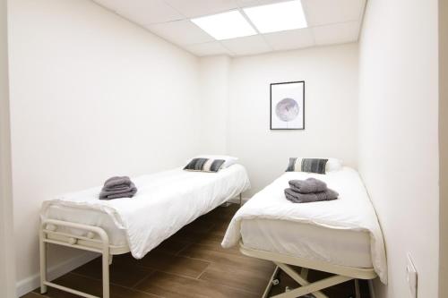 two beds in a room with white walls at המלך גורג סוויטה in Jerusalem