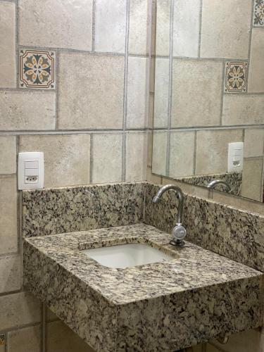 a bathroom counter with a sink with a faucet at Hotel Uirapuru in Alexânia