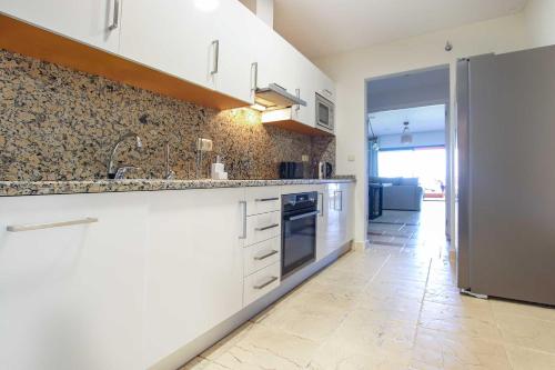 a kitchen with white cabinets and a tile floor at Apartamento en residencial de lujo Los Flamengos in Estepona