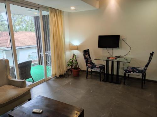 uma sala de estar com uma televisão e uma mesa e cadeiras em Goan Fiesta 1BHK Pool View at Eternal Wave CALANGUTE em Calangute
