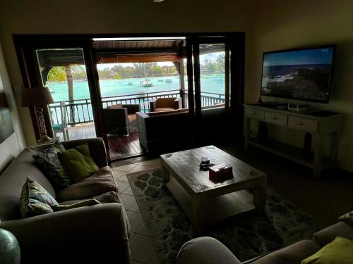 a living room with a couch and a table and a television at Grand Baie Beach Penthouse in Grand Baie