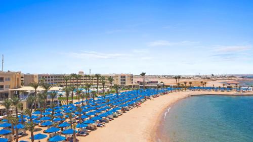 una playa con sombrillas azules y el océano en Beach Albatros Aqua Park - Hurghada, en Hurghada