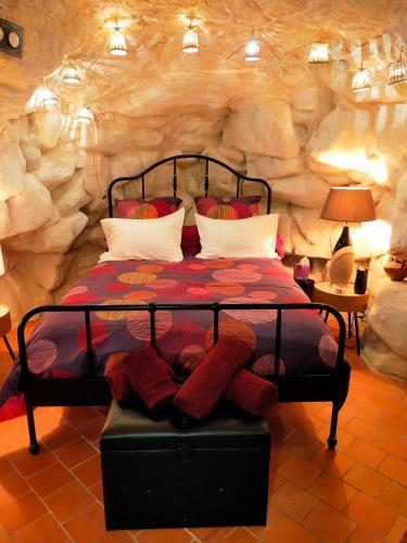 a bedroom with a bed in front of a stone wall at Les troglos de Cumeray in Le Thoureil