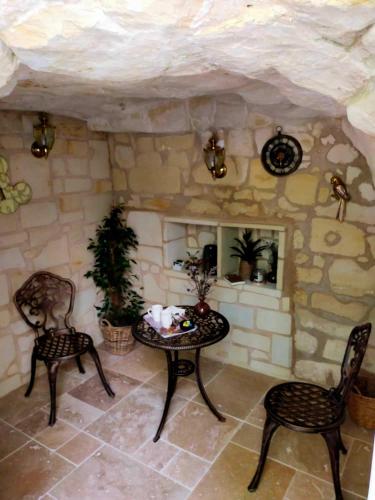 Habitación con mesa, sillas y pared de piedra. en Les troglos de Cumeray, en Le Thoureil