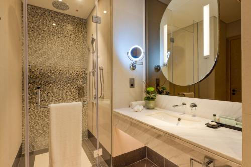 a bathroom with a sink and a shower and a mirror at Embassy Suites By Hilton Doha Old Town in Doha