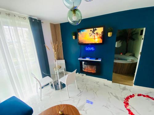 uma sala de estar com televisão numa parede azul em Exotic spa em Poissy