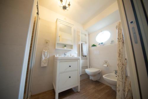 Baño blanco con lavabo y aseo en Appartamento "Bella vista" sul Lago di Como, en Faggeto Lario 