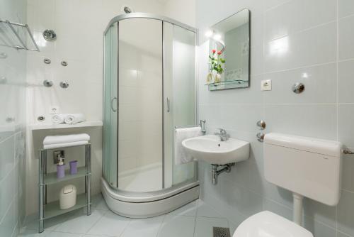 a white bathroom with a shower and a sink at Apartments Plazibat in Hvar