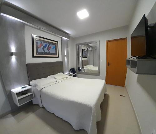 um quarto com uma cama branca e um espelho em Santa House no Centro em Santa Cruz do Sul