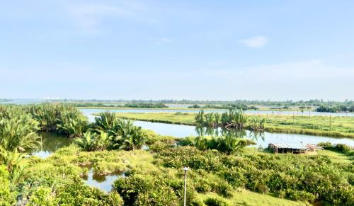 a river in the middle of a field with trees at The Quin Riverside Villa in Hoi An