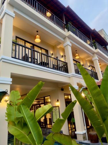 a house with a balcony and some green plants at The Quin Riverside Villa in Hoi An