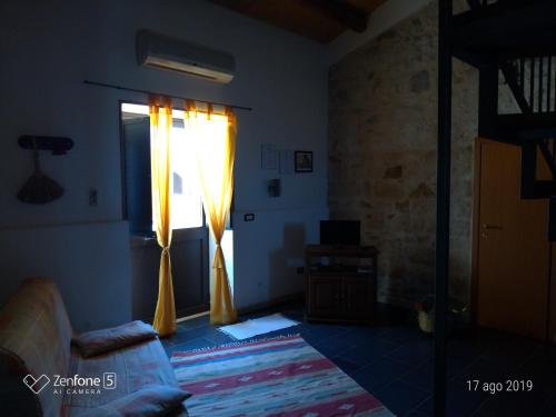 ein Wohnzimmer mit einem Fenster mit gelben Vorhängen in der Unterkunft I Dammusi in Santa Croce Camerina