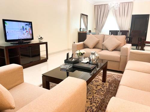 Sala de estar con 2 sofás y TV en Al Gosaibi Hotel-Villa en Al Khobar