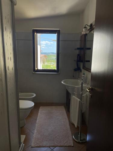 a bathroom with a toilet and a sink and a window at Agriturismo Le Viole in Barolo