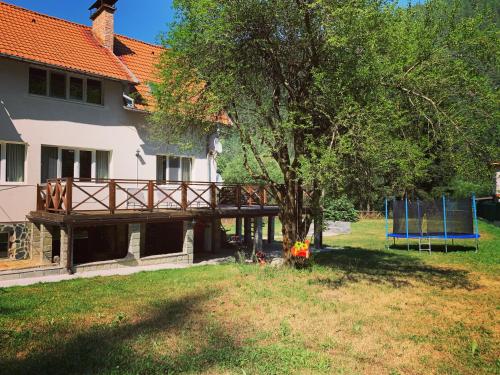 a house with a wooden deck next to a tree at Villa Aquila in Beli Iskar