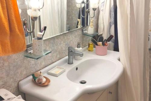 ein Badezimmer mit einem weißen Waschbecken und einem Spiegel in der Unterkunft Unique & cozy seaview apartment. in Loutraki