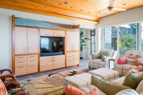 a living room with a tv and a couch and chairs at Beautiful 3 story 8,000 sq ft Oceanside Mansion in Nevis