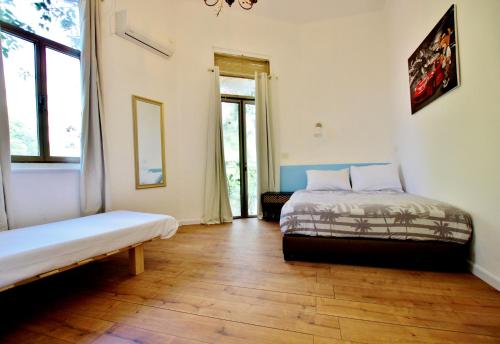 two beds in a room with wooden floors and windows at beautiful 3 rooms apartment at neve tzedek in Tel Aviv