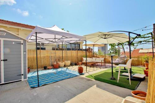 einen Hinterhof mit einem Pool mit Sonnenschirmen in der Unterkunft beautiful 3 rooms apartment at neve tzedek in Tel Aviv