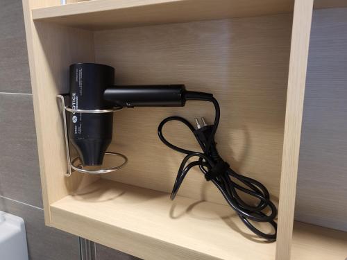 a black hair dryer sitting on a shelf at ELBON the stay Haeundae beach ocean view in Busan