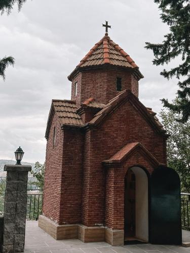 a brick church with a cross on top of it at Apple cozy hotel in Tbilisi City