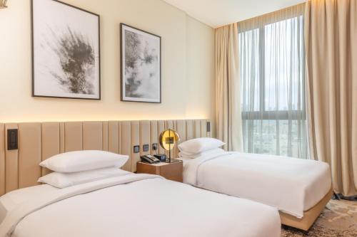 2 camas en una habitación de hotel con ventana en Embassy Suites By Hilton Doha Old Town, en Doha
