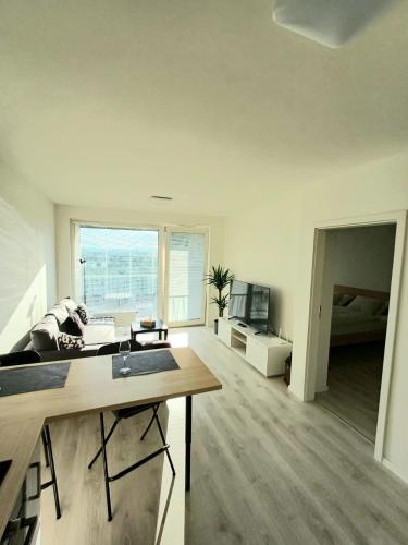 Nový, klimatizovaný, útulný apartmán s garážou, 5 min od letiska في براتيسلافا: غرفة معيشة مع طاولة وأريكة