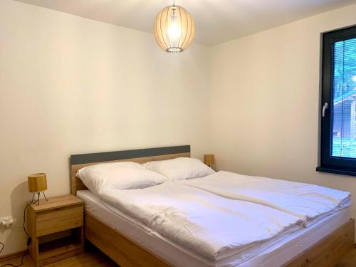 a bedroom with a bed with white sheets and a window at Chata Horskej služby Trangoška - Chopok juh in Horná Lehota