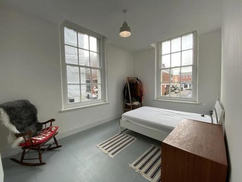 a bedroom with a bed and a chair and two windows at 2-bed in central Margate in Kent