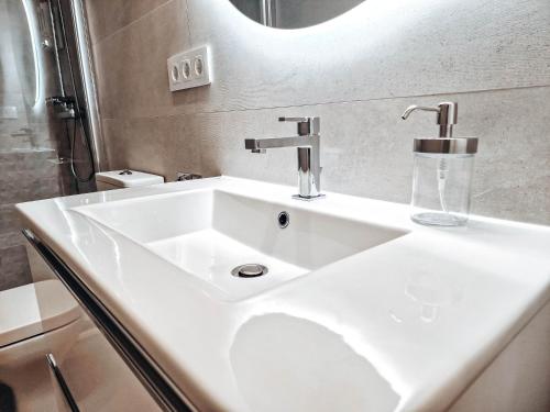 Un lavabo blanco en un baño con espejo. en Apartamento TIENDAS 8, en Almería