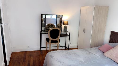 a bedroom with a chair and a desk and a bed at La chambre de Lou in Chatou