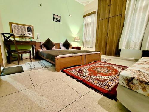a bedroom with a bed and a desk and a rug at UVs Homestay in Haridwār