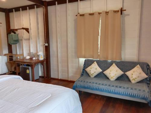 a bedroom with a bed and a blue bench with pillows at The Best Bungalow in Ban Bang Chak