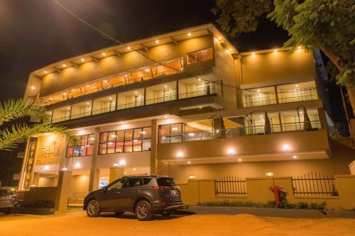 un coche aparcado delante de un edificio por la noche en The Hut Restaurant & Boutique Hotel, en Kigali