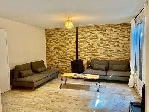 una sala de estar con 2 sofás y una pared de ladrillo en Cosy room - Maison covoyageurs, en Pessac