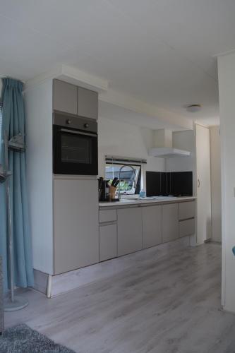 uma cozinha com armários brancos e um micro-ondas em Veluwe chalet em Putten