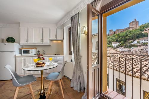 a kitchen with a table and chairs and a balcony at ADANAR-Apartamentos Muralla Zirí in Granada