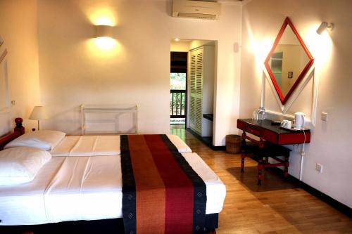 a bedroom with a bed and a desk and a mirror at Hotel Hill Top in Kandy