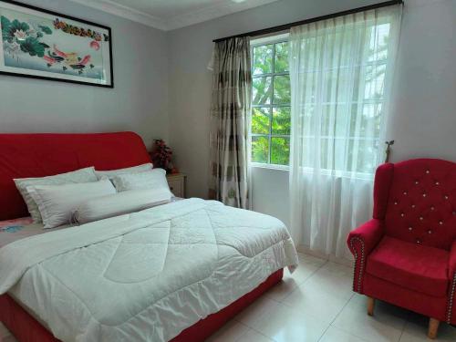 a bedroom with a bed and a red chair and a window at Trails of Kampar Villa Homestay in Kampar