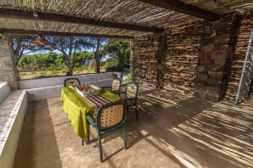 une table et des chaises sur une terrasse avec un mur en pierre dans l'établissement Dammuso i Pini di Kaddiuggia (CIR19081014C224053) & Dammuso di Mena (CIR 19081014C224052, à Pantelleria