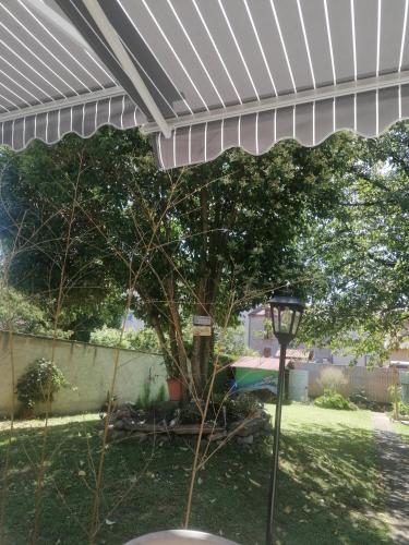 a white pergola in a yard with a tree at Chambres dans maison familiale in Saint-Girons