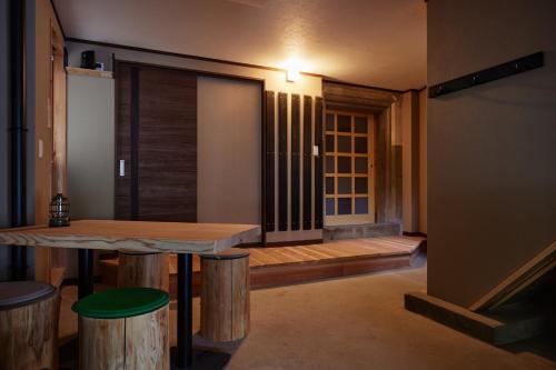 a room with a table and stools and a door at 民泊のらりくらり in Ajima