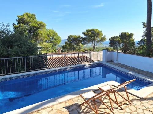 a swimming pool with two chairs and a fence at Magnífica casa con vistas al mar y piscina privada in Girona