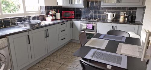 a kitchen with white cabinets and a table in it at HESFORD B in Manchester