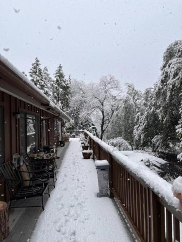 a snow covered sidewalk next to a building with a railing at Ponderosa Creekside Retreat in Mariposa